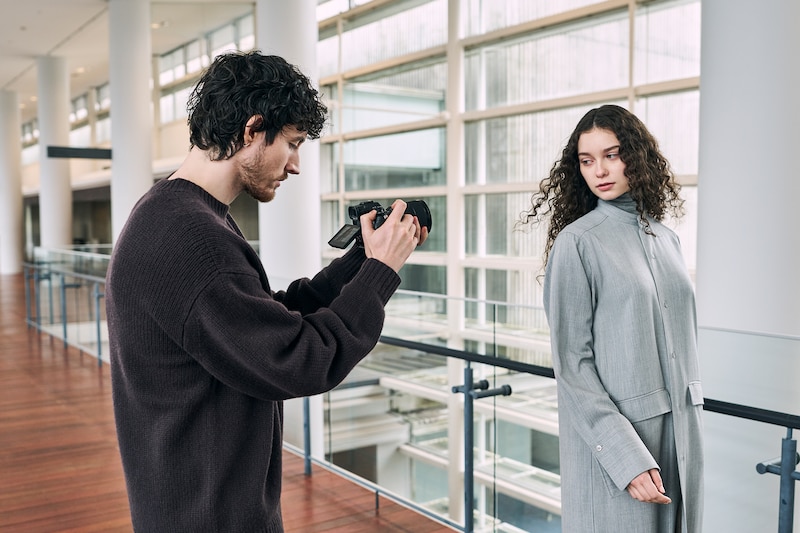 Imagen de uso de un videógrafo que sostiene una α7R VI y graba a una mujer mientras la sigue.