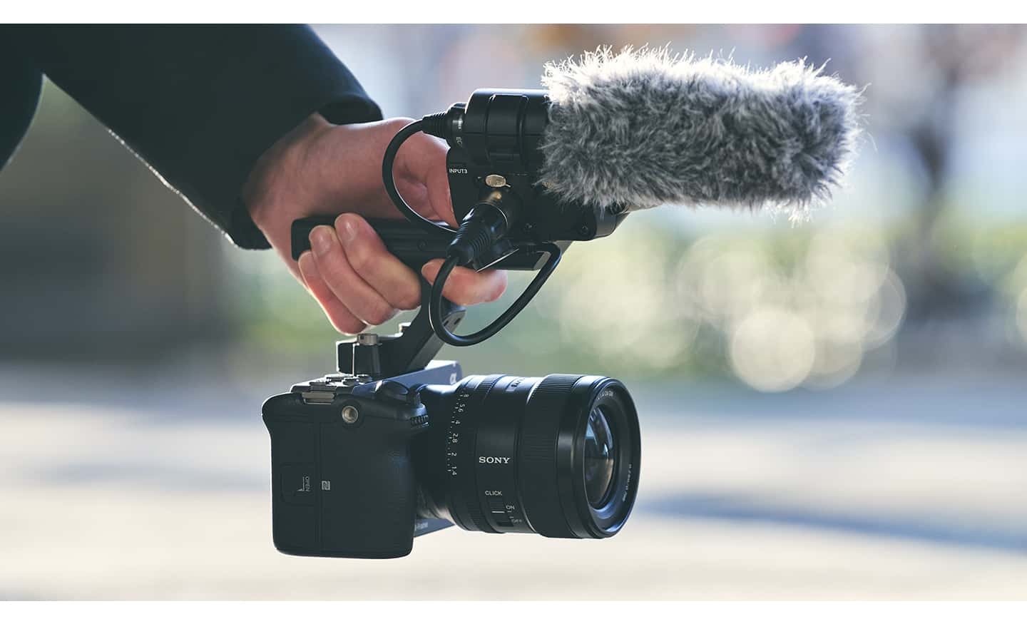 Imagen de uso de una persona que sostiene la FX3 con asa, adaptador XLR y micrófono direccional